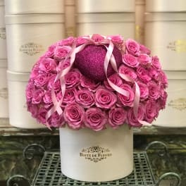 Pink roses arranged around a glittery heart in a white hat box