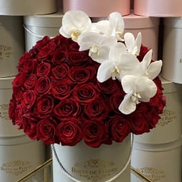 Red roses with white orchids in a round hat box