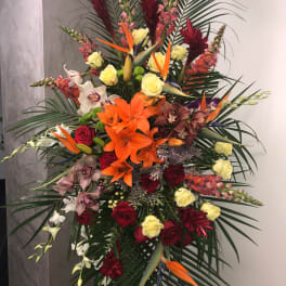 Tall tropical floral spray with orange lilies, roses, and orchids