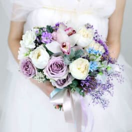 Bride holding a pastel bouquet of roses, orchids, and purple filler flowers