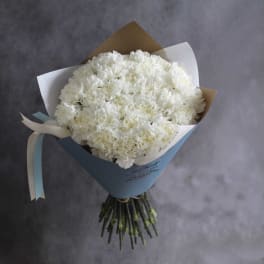 Bouquet of white carnations wrapped in pastel paper with ribbon
