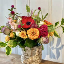 Colorful mixed flower arrangement in a birch bark vase
