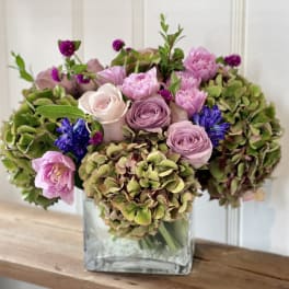 Pink and purple bouquet in a square glass vase