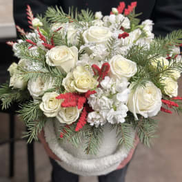 White roses with red accents in a round container