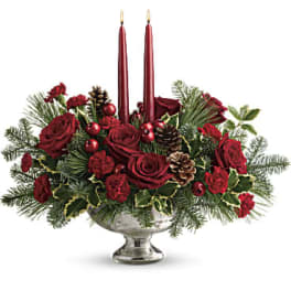 Red roses and holiday greenery in a silver bowl with two red candles