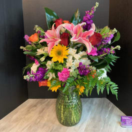 Mixed bouquet of lilies, roses, and daisies in a glass vase