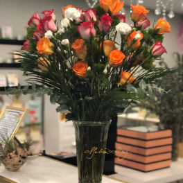 Bouquet of orange and pink roses in a clear glass vase