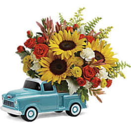 Bouquet of sunflowers and red roses in a blue toy truck