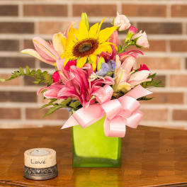 Mixed bouquet with a sunflower and pink lilies in a green vase