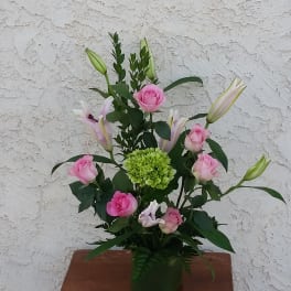 Pink roses and lilies arranged in a green vase