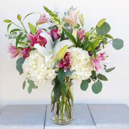 Bouquet of pink lilies, white hydrangeas, and eucalyptus in a glass vase