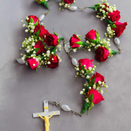 Rosary with red rose buds and white baby's breath around a crucifix