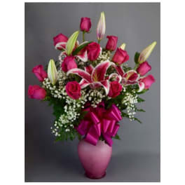 Pink roses and lilies in a pink vase with a ribbon