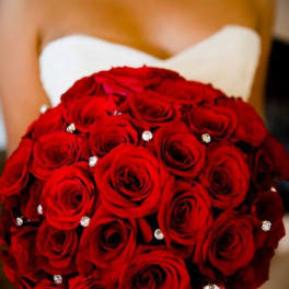 Bride holding a bouquet of red roses with jeweled accents