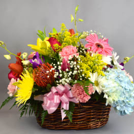 Colorful mixed flower basket with a pink ribbon bow