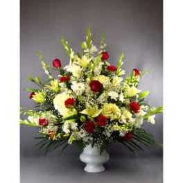 Large red, white, and yellow floral arrangement in a white vase