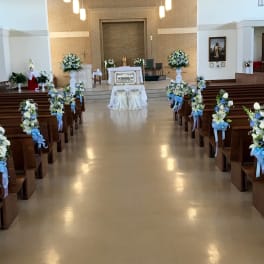 Church aisle decorated with blue and white floral arrangements for a ceremony
