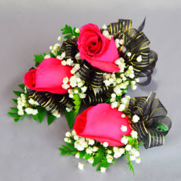 Two pink rose corsages with black ribbon and white filler flowers