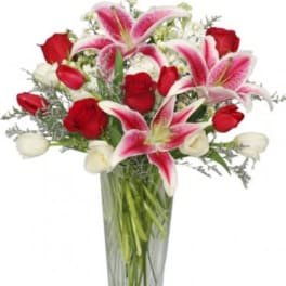 Bouquet of pink lilies and red roses in a clear glass vase