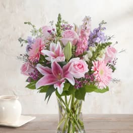 Pink lilies, roses, and daisies in a clear glass vase