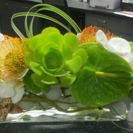 Green and white floral arrangement in a rectangular glass vase