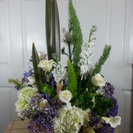 Tall floral arrangement with white roses, calla lilies, and purple filler flowers