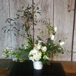 Tall white floral arrangement in a white vase with airy greenery