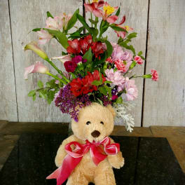 Teddy bear with a mixed flower arrangement and pink ribbon
