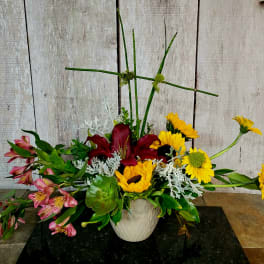 Mixed floral arrangement in a white vase with lilies and sunflowers