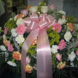Large floral wreath with pink ribbon and mixed pink, white, and peach flowers