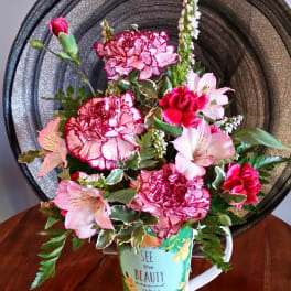 Pink and white flower arrangement in a decorative mug