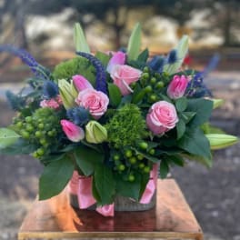 Pink roses and tulips in a low vase arrangement with blue accents
