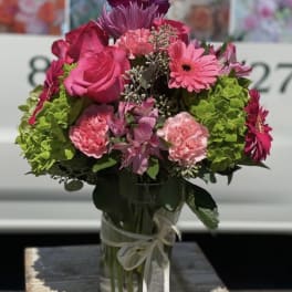 Pink and magenta bouquet in a glass vase with a ribbon