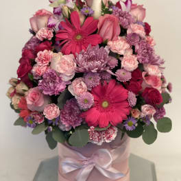 Pink and purple mixed bouquet in a round pink box with a ribbon