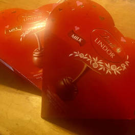 Two heart-shaped Lindor chocolate boxes on a wooden surface