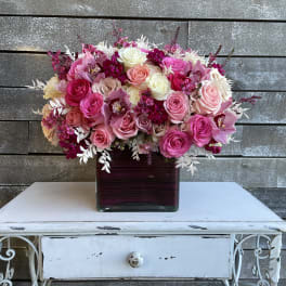 Pink and white rose bouquet in a square glass vase