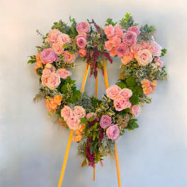 Heart-shaped floral wreath on an easel with pink and lavender roses