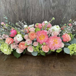 Low floral arrangement of pink and peach roses with large pink blooms