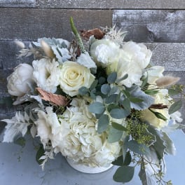 White floral bouquet in a low white container with eucalyptus