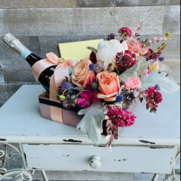 Flower arrangement in a gift box with a champagne bottle