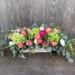Low floral centerpiece with pink and coral roses and green hydrangeas