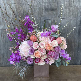 Large bouquet of pink and purple roses with orchids in a square vase