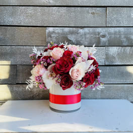 Bouquet of red and blush roses in a white hat box with a red ribbon