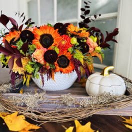 Bright autumn floral arrangement in a white bowl beside a white pumpkin decor piece