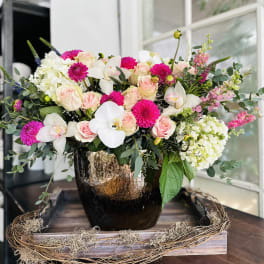 Pink roses and white orchids in a dark vase with white hydrangeas