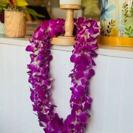 Purple orchid lei draped over a wooden stand