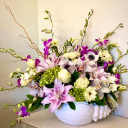 Mixed pink, white, and purple flowers in a white vase