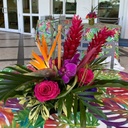 Tropical floral centerpiece with pink roses, purple orchids, and red ginger flowers