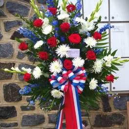Standing floral spray with red roses, white daisies, and blue flowers
