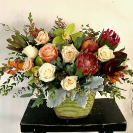 Mixed bouquet of roses and protea in a green vase